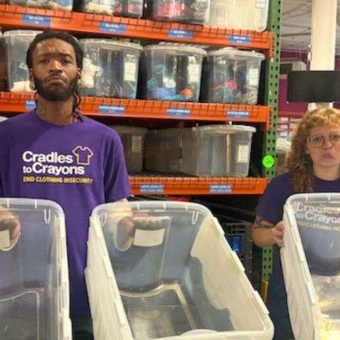 Cradles to Crayons volunteers holding up empty clothing bins