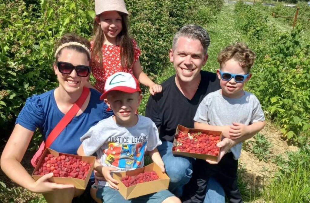 A family of five holds their cache of hand-picked raspberries at Hellericks Family Farm.