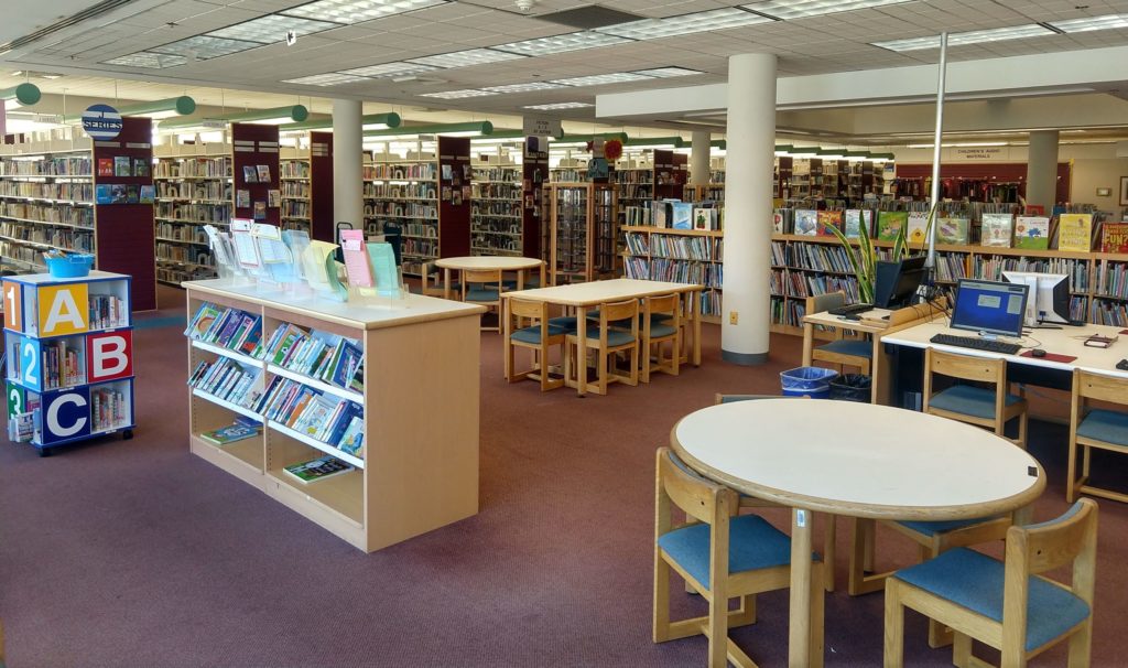 Upper Merion Library children's area showing wooden tables and chairs, computers and many books.