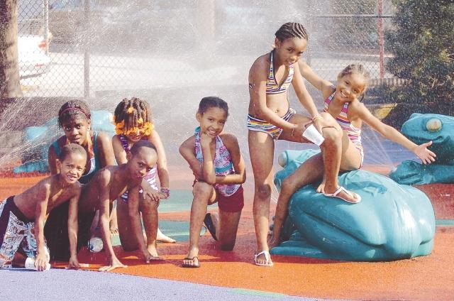 Children play at the splash pad in the John O. Greene Memorial Park.