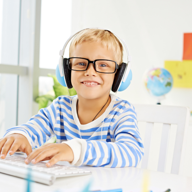 Little boy smiling with headphones at his PC computer.