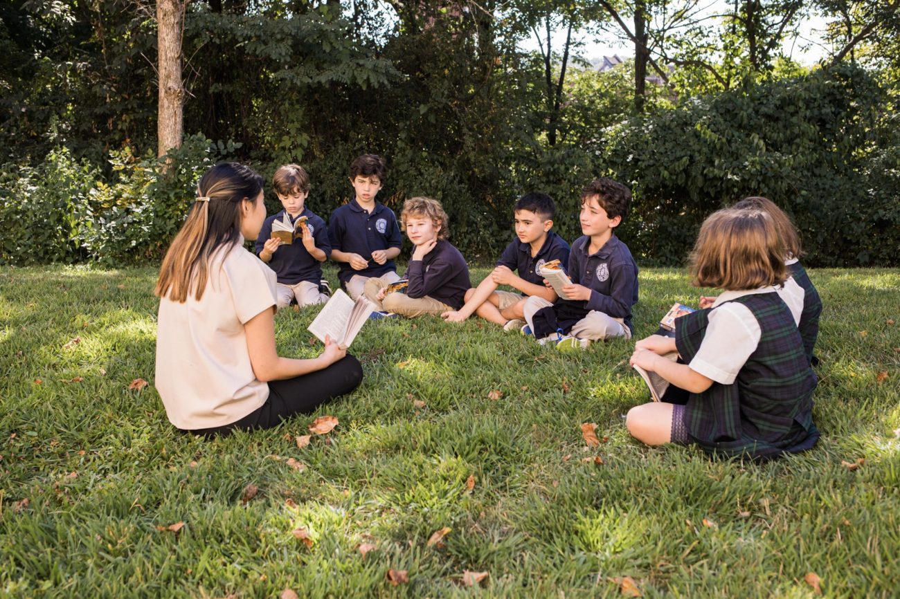 students reading a book in the grass