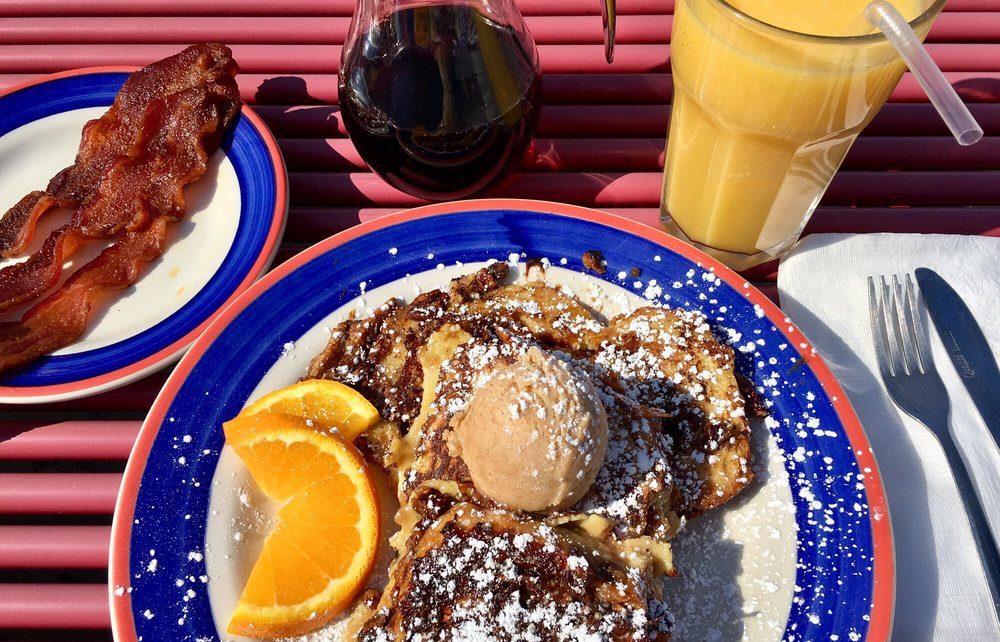 Photo of sticky bun french toast, syrup bottle, oj, and bacon courtesy of Lauren L on Yelp