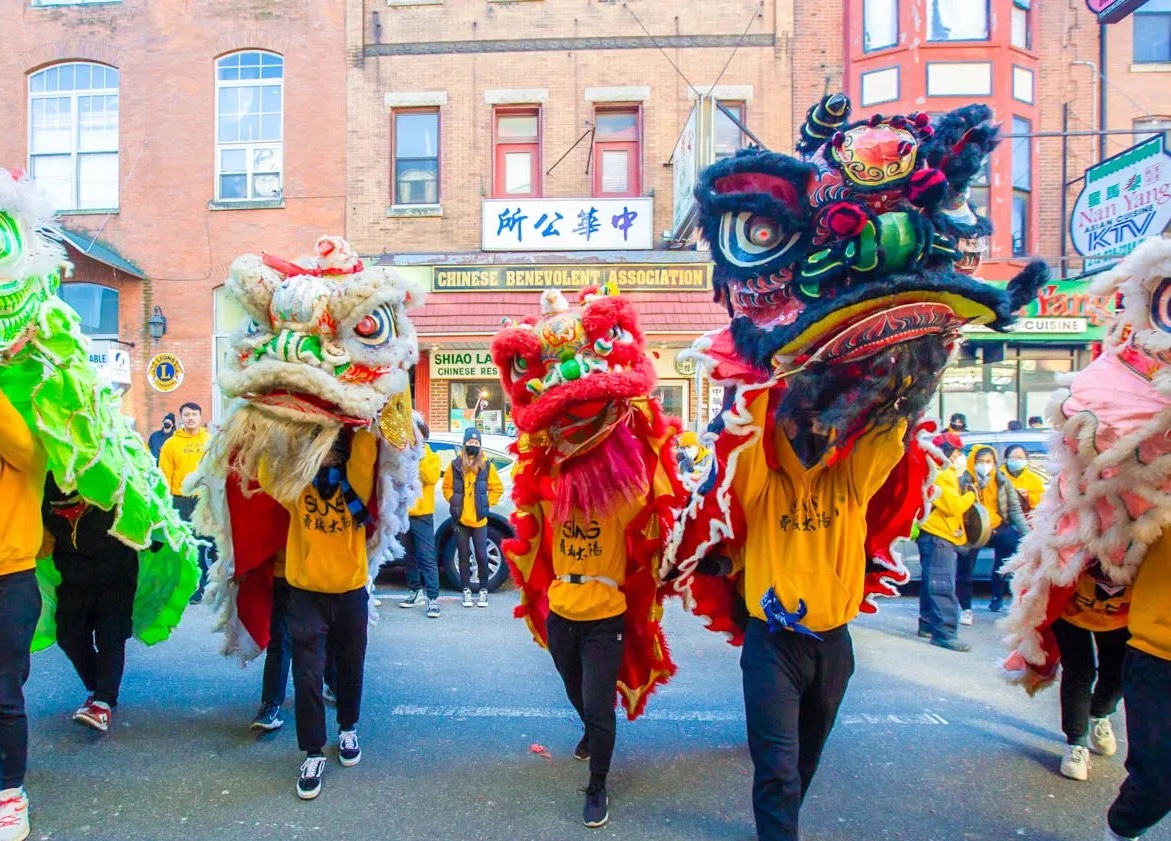 Philadelphia Suns performers wear red, blue, green. and yellow dragon and lion head costumes in Chinatown for Lunar New Year.
