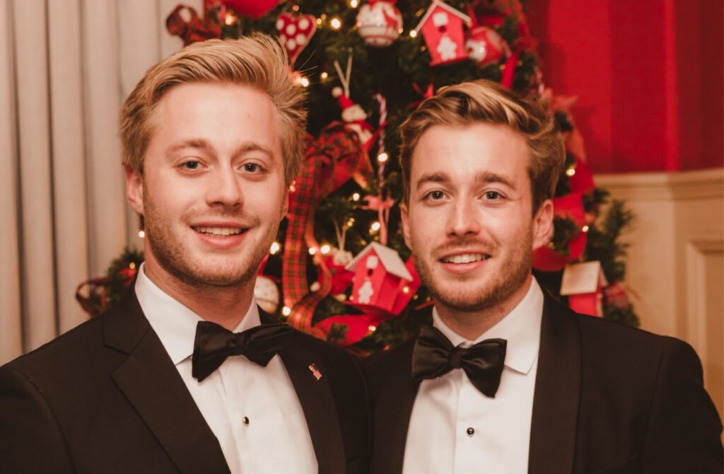 two Caucasian brothers in front of a christmas tree.