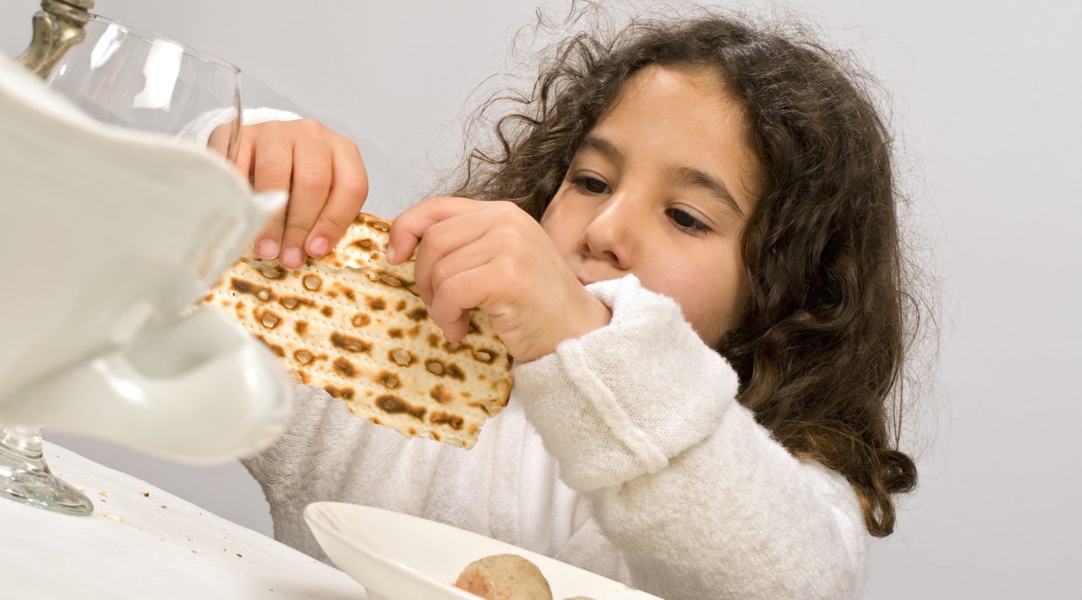 A young girl holds matzah at a Passover seder.