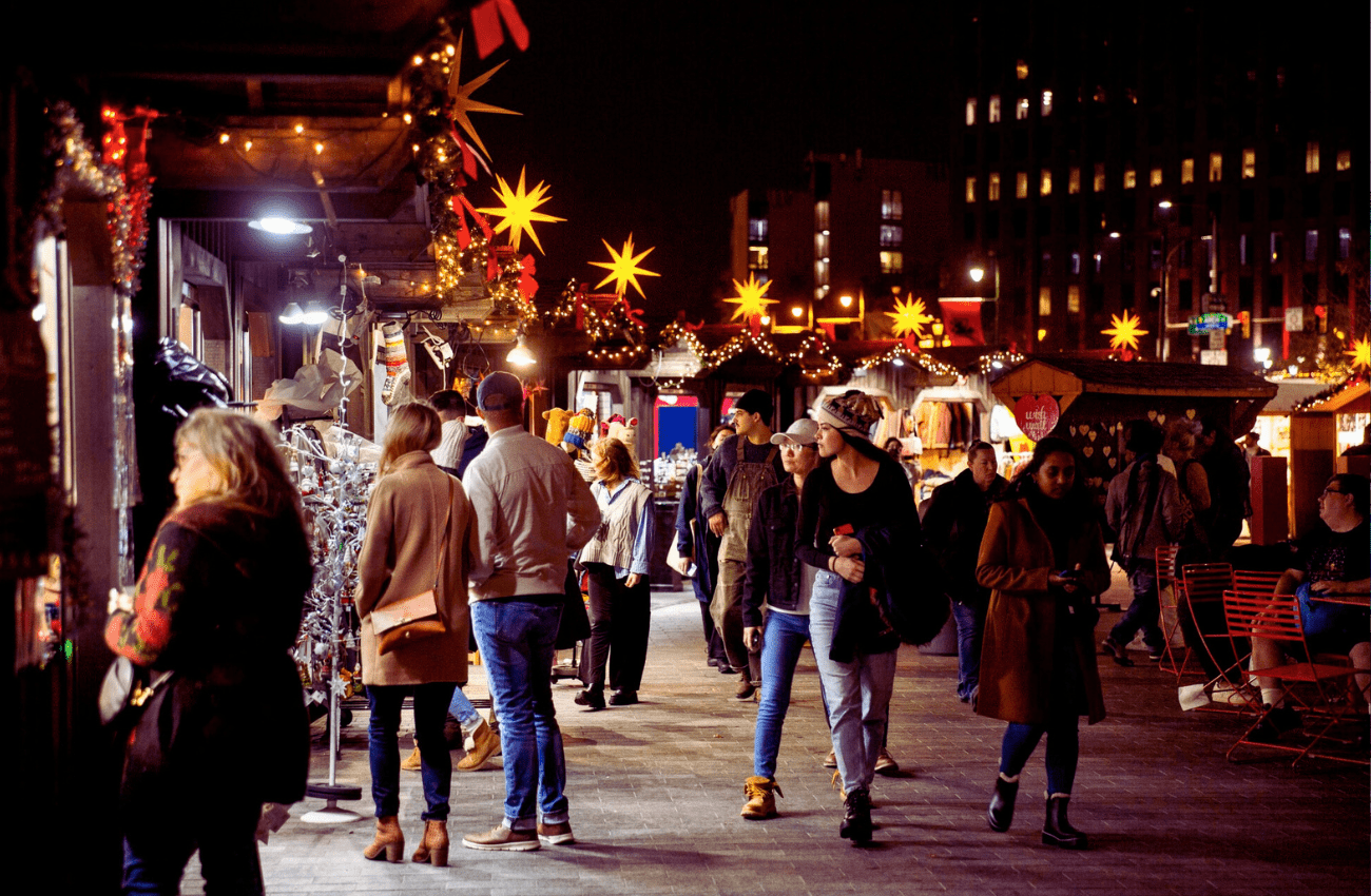 People stroll at night among twinkling lights at Christmas Village in Philadelphia, a holiday market.