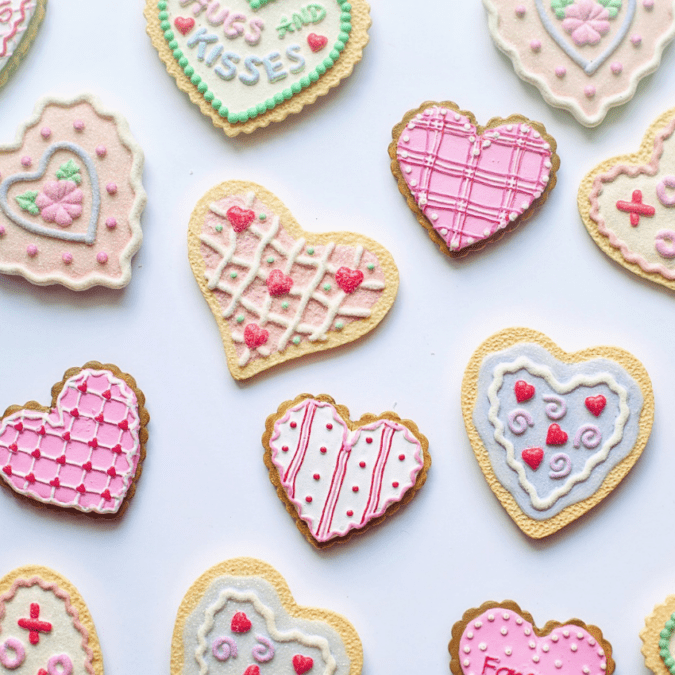 An assortment of heart-shaped Valentine's Day cookies with pink, red, white, green, and blue icing decoration.