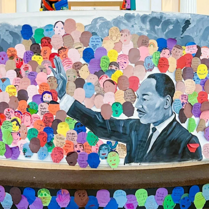 A painting depicts Martin Luther King, Jr. waving to a crowd in honor of MLK Day.