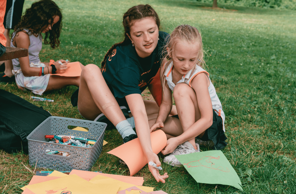 Two campers doing an art project in the grass at summer camp