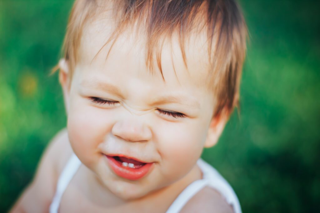 baby girl laughing with two teeth and close her eyes closeup portrait. Focus on eyes