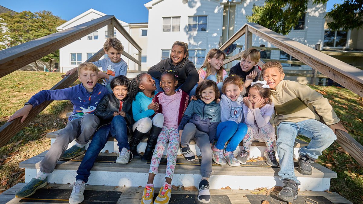 Group of lower school students posing on wooden steps.