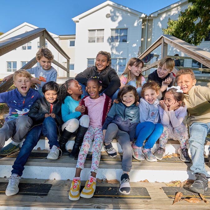 Group of lower school students posing on wooden steps.