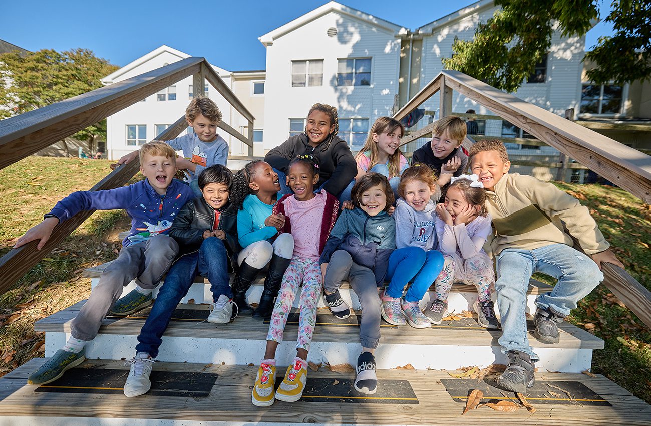 Group of lower school students posing on wooden steps.