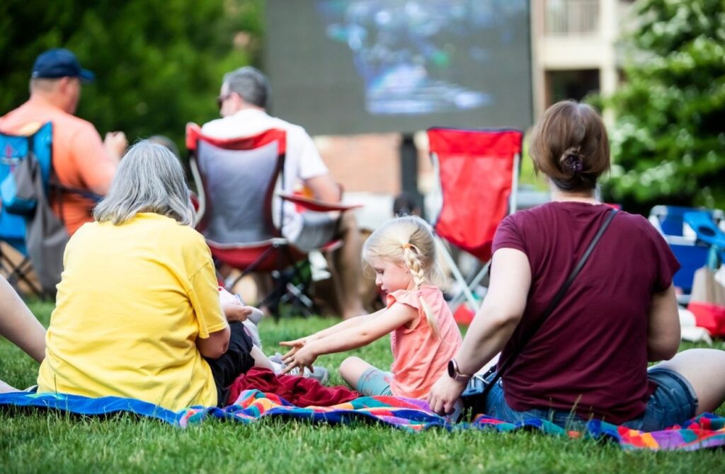 A little girl and her mother and grandmother watch an outdoor movie at Eagleview Town Center in Exton.