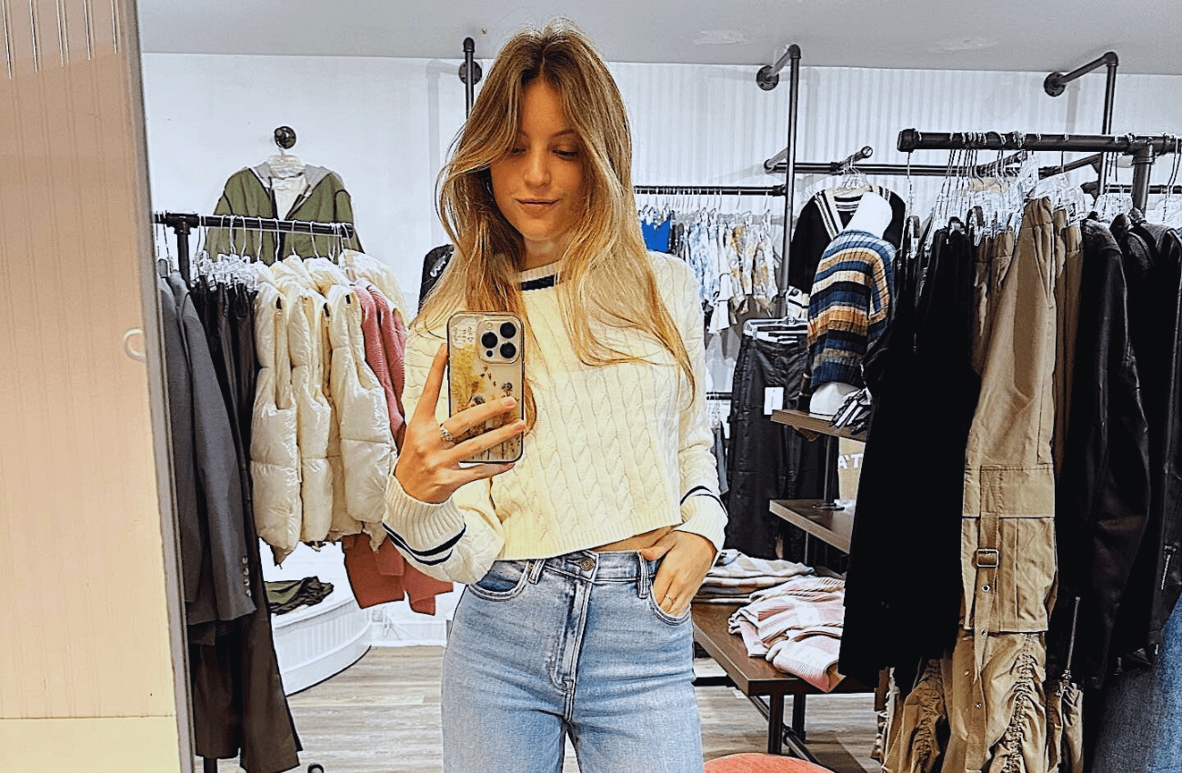 A girl taking a mirror selfie shopping for teen clothing.