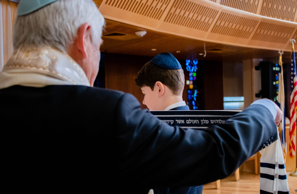 Grandfather putting a prayer shawl on grandson for a bar mitzvah