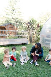 preschool students and teachers interacting in an outdoor classroom area.