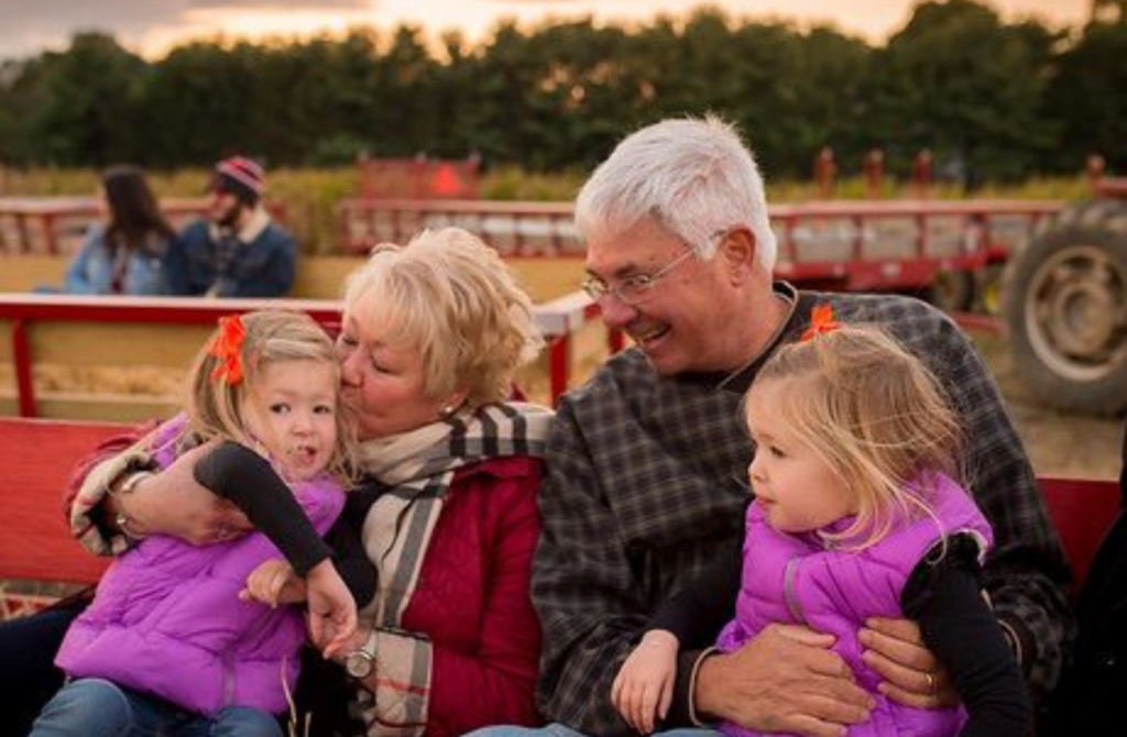 Two little girls on a hayride with their granparents at a fall festival.