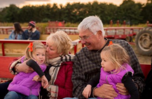 Two little girls on a hayride with their granparents at a fall festival.