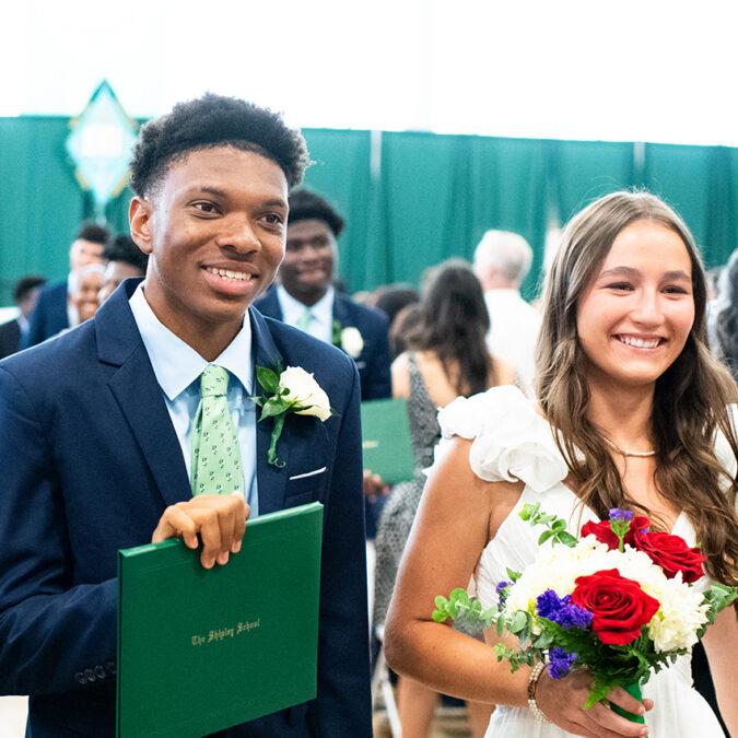 Two high school graduates receiving diplomas