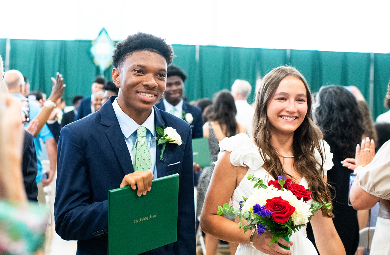 Two high school graduates receiving diplomas