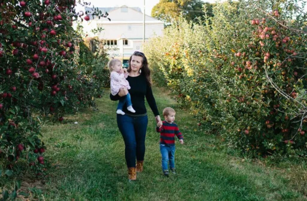 Family strolling through an apple orchard on a fall morning near the Main Line