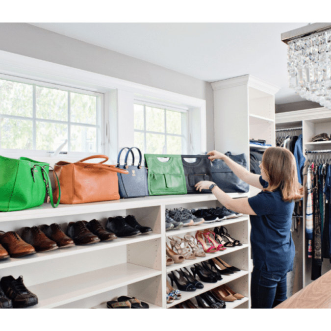 A home organizers straightens up handbags and shoes in a large, walk-in closet.