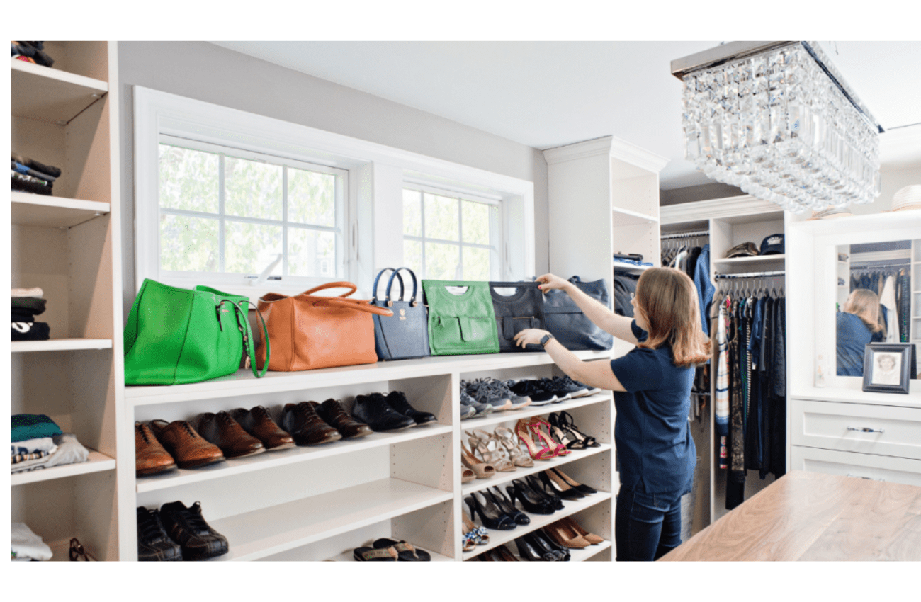 A home organizers straightens up handbags and shoes in a large, walk-in closet.