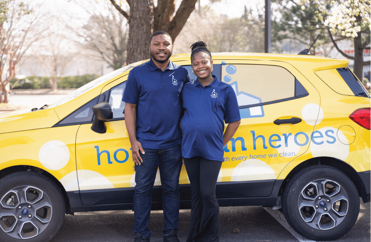 Two business owners standing in front of their branded vehicle