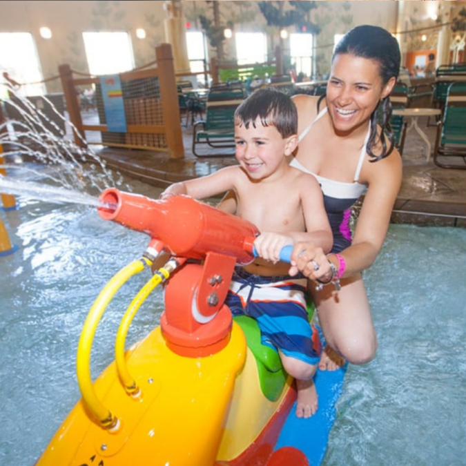 A mother and son play on a sprayer at the Great Wolf Lodge, an indoor water park.