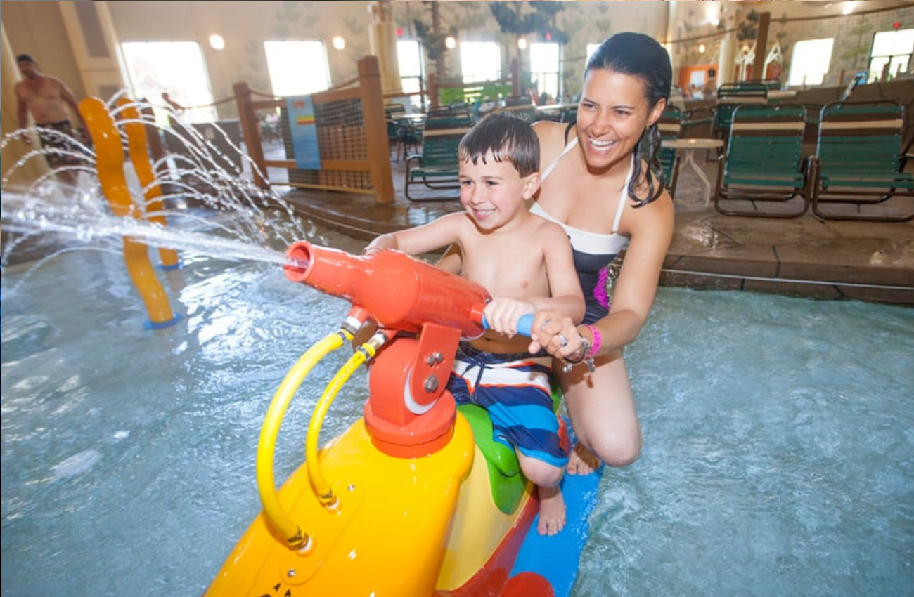 A mother and son play on a sprayer at the Great Wolf Lodge, an indoor water park.