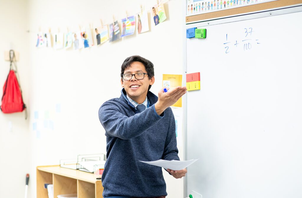 A teacher standing at a white board teaching a class.