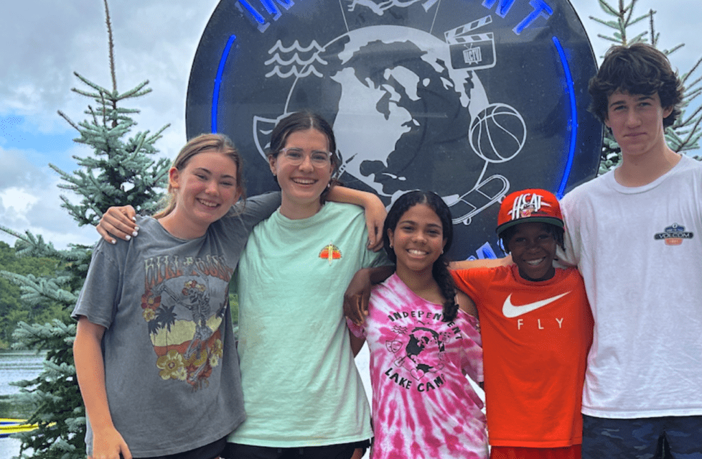 Five children of diverse backgrounds with arms around each other, an example of summer camp benefits at Independence Lake Camp.