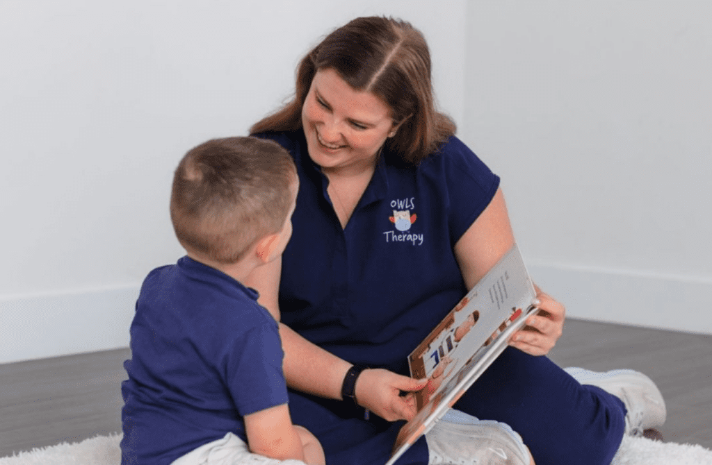A speech therapist reading a picture book to a male child for kindergarten readiness.