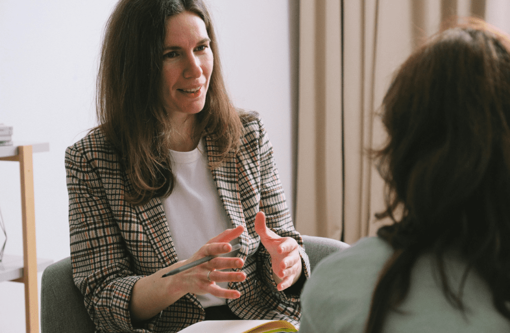 A female health practitioner in her 40s speaks with a female patient about perimenopause support.