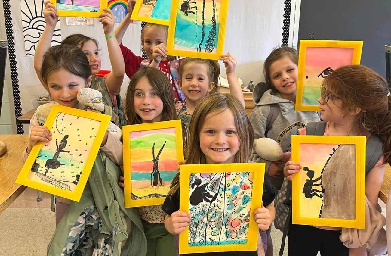 Kids hold up their artwork in Abrakadoodle's art classes for kids in the afternoon.