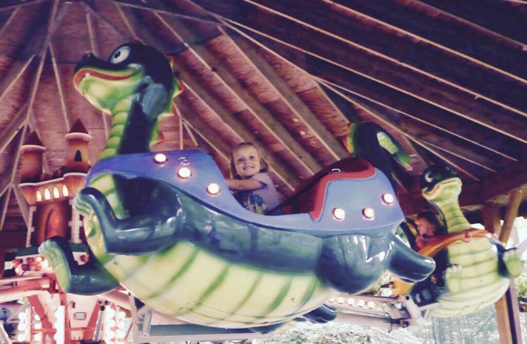 A little girl riding the Happy Dragon Ride at Storybook Land.