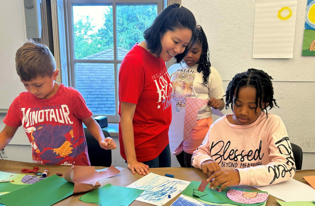 A teacher encourages students with a cut, paste and drawing project at one of Main Line Art Center's art classes for kids in the Greater Philly area.