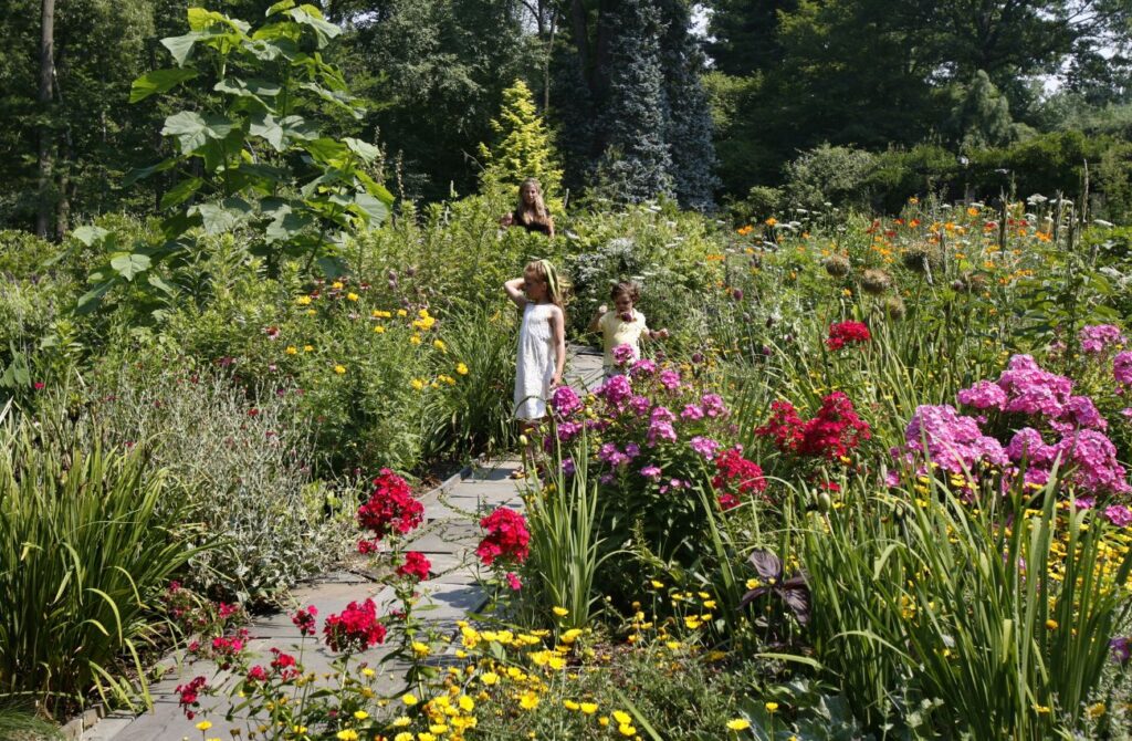 Two young girls and their mother strong a flower-filled garden path at Chanticleer garden in Wayne, PA.