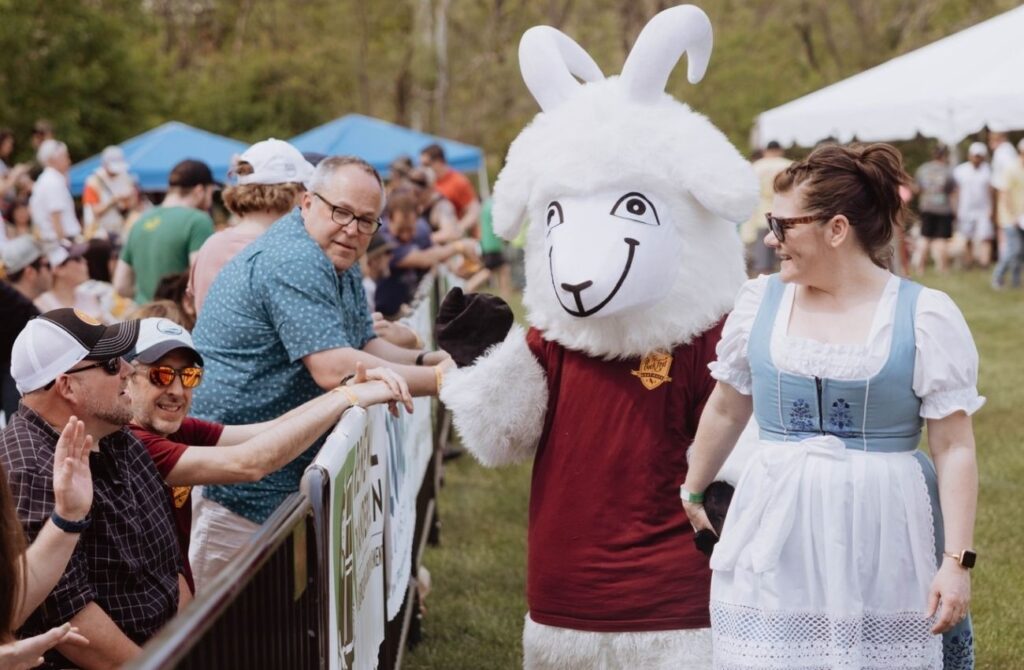 The goat mascot greets the crowd with a woman in a German-style dirndl dress during Sly Fox Goat Races.