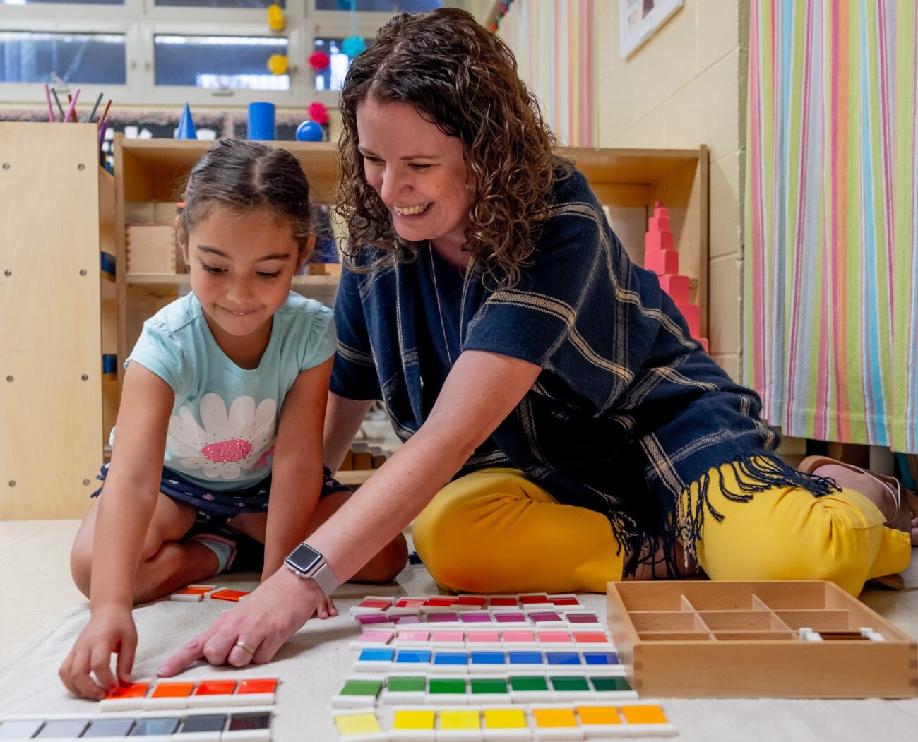 A teacher helping a preschool student with color matching work
