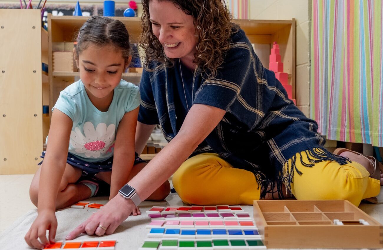 A teacher helping a preschool student with color matching work
