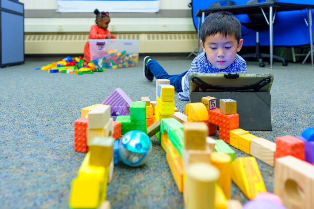 Preschool child assessing his block building with software on an ipad.