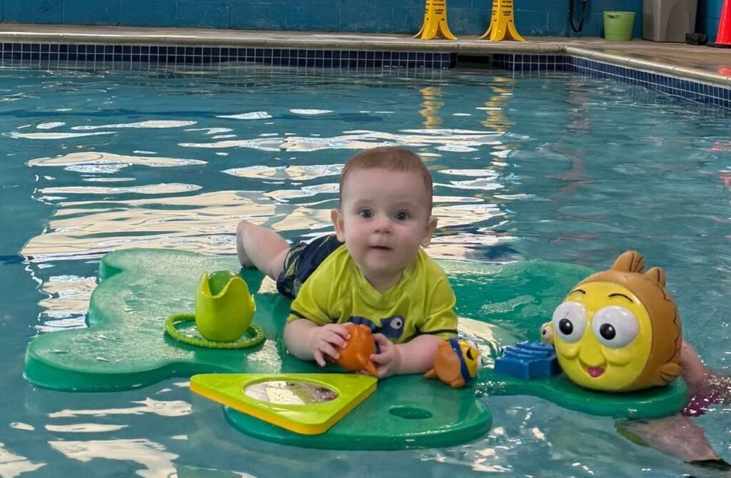 A baby on a floatie during a Goldfish Swim School baby swim class. 