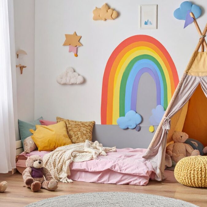 A corner of a child's bedroom with sensory-friendly elements including a tent, a wall mural, and soft toys.