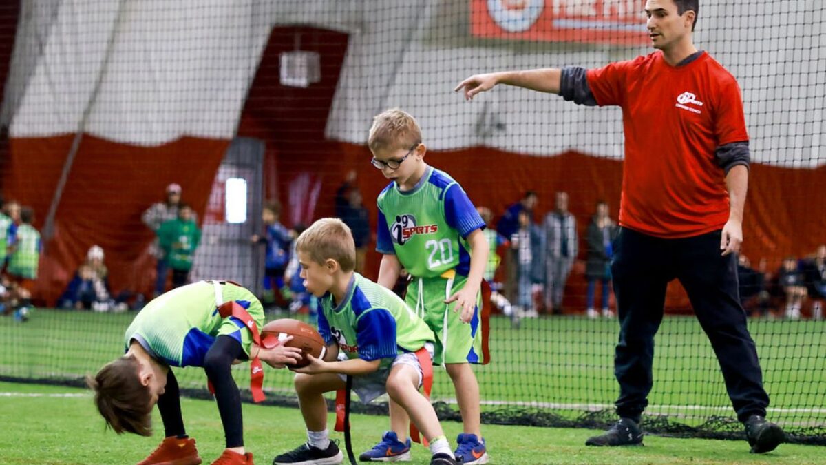 Little boys practice football plays with a coach at a winter sports class.
