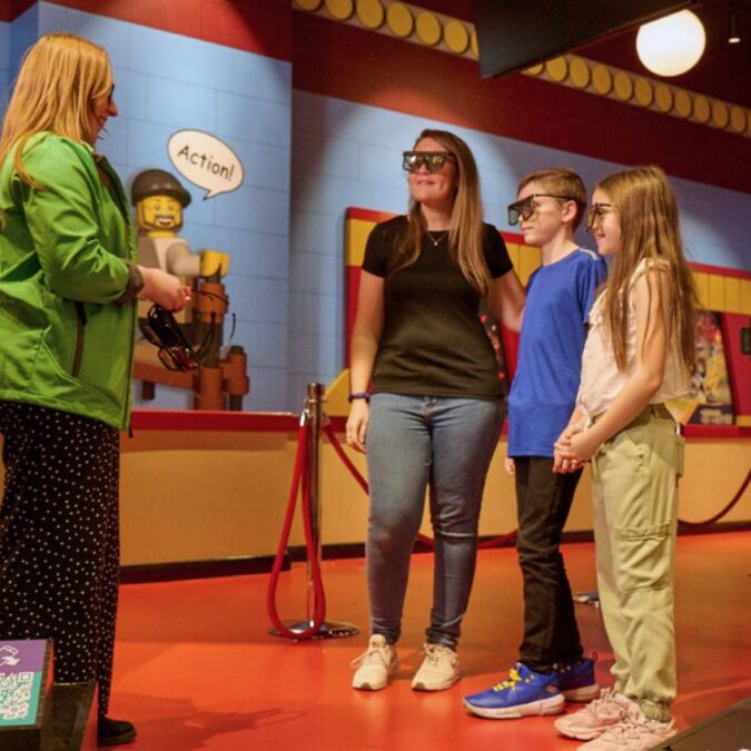 A mom and two kids wear special glasses to watch a 4D movie at Legoland Discovery Center.