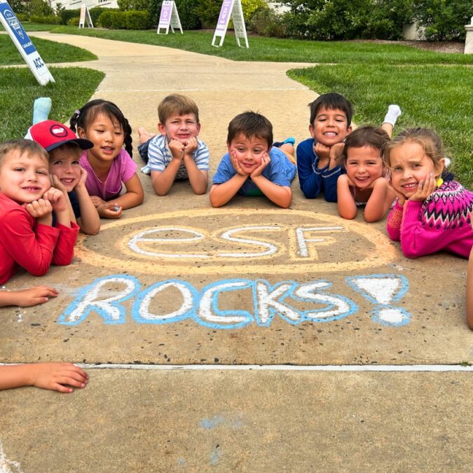 young campers pose on the sidewalk around chalk art that says ESF rocks