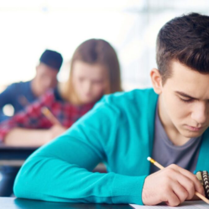 High school students sit at tables taking a test.